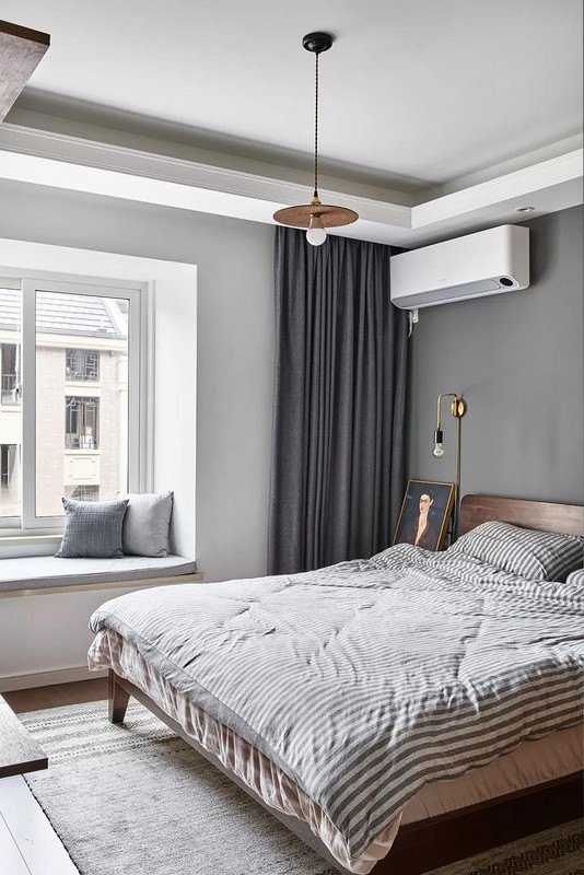 主卧以灰白两色为基调，配以深色木质大床与灰白条纹床品，营造静谧安逸的睡眠氛围。