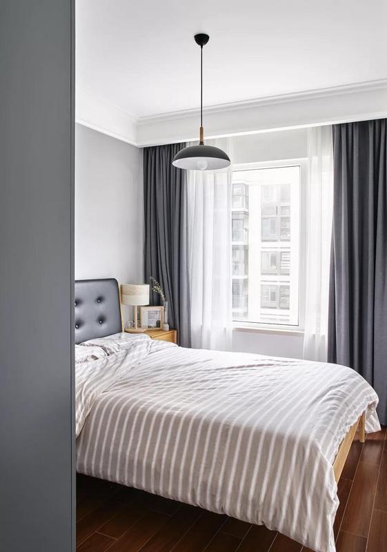 次卧，灰色窗帘与衣柜简洁优雅，搭配黑色的皮艺靠背床及轻松舒适的床品，呈现出一个随性自在的睡眠空间。