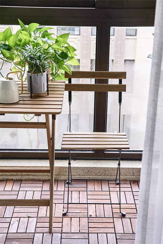  阳台地面铺设防腐木地板，搭配一套木质铁艺休闲桌椅，在绿植的烘托下，充满了清新自然的气息。