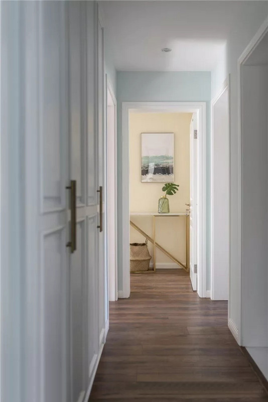 走廊量身定做了柜子，隐藏着巨大的收纳空间，嵌入式的设计以及白色的柜门保持走廊整洁的观感。