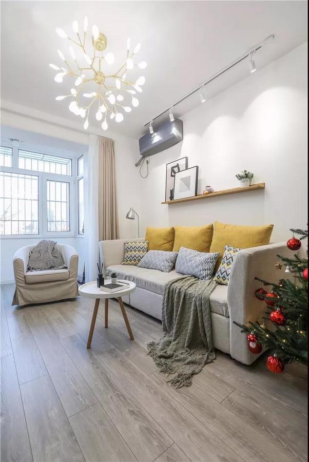 萤火虫吊灯轻盈柔和，沙发上加几个暖黄色的靠枕，气氛立刻就变的温暖起来。迷你茶几，搭配灰色木地板，自然而舒适。